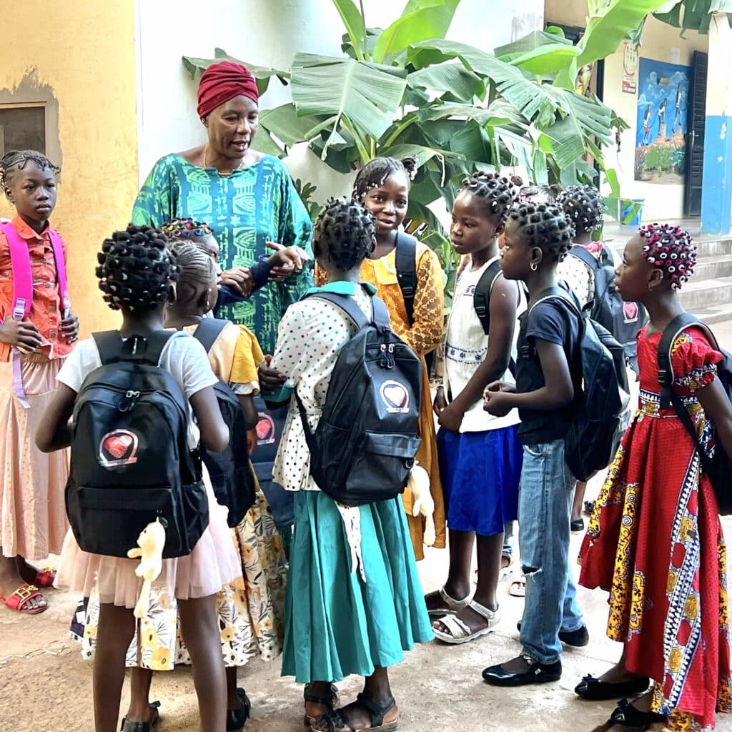 Frau steht mit einer Gruppe Kinder vor Schule